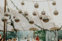 03 a cozy wedding lounge with lots of disco balls hanging over it that bring a cool party feel to the space