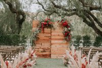06 The wedding ceremony space was done with greenery, red blooms and pampas grass around