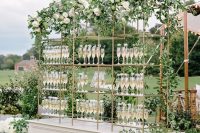 08 a beautiful drink stand of a white base and metal and glass shelves, lush greenery and white blooms is refined