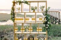 14 a tall wooden stand with lots of shelves, greenery and neutral blooms and drinks in glasses