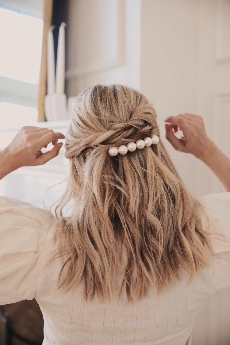 a half updo with twists, a bump and loose waves and accented with a large pearl hair barrette