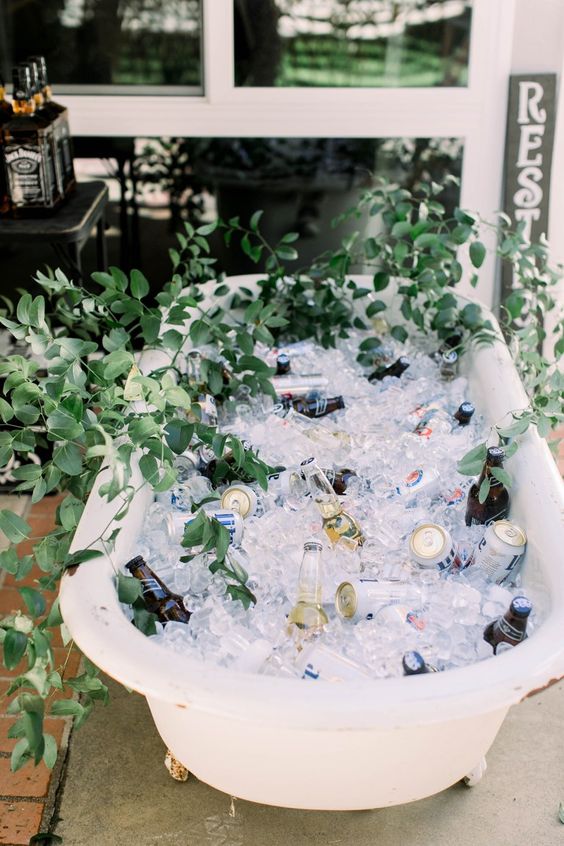 a bathtub filled with ice and greenery, with various drinks for cooling is a cool idea
