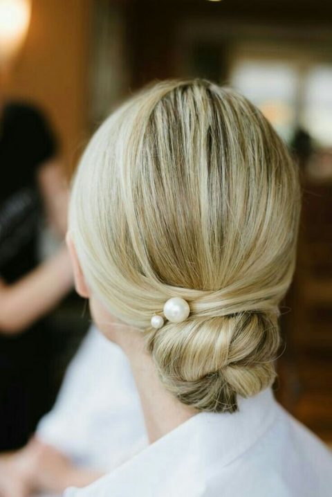a low and tight bun with a sleek top and large pearl pins is a gorgeous and fresh idea for a modern or minimalist bride