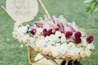 20 a cart with lots of fresh blooms and leaves and fresh drinks in bottles plus a wooden sign