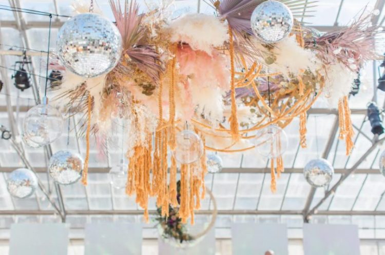 a wedding arrangement of dried fronds and leaves, pampas grass, feathers, yarn and disco balls for a unique look