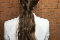 24 a wavy twisted low ponytail with some locks down and large pearl pins for a bolder accented look