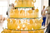 25 a stylish round glass stand with candles and bright blooms and drinks in jars is a lovely idea