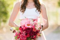 a beautiful ombre wedding bouquet from light pink to hot pink and red and burgundy blooms and greenery makes a statement