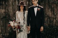 a boho lace sheath wedding gown with a plunging neckline, a train and long fringe plus a brown hat