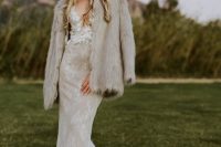 a catchy bridal look with a lace mermaid wedding dress, a neutral faux fur coat and a black hat