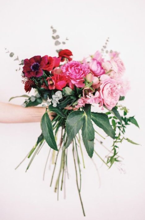 a chic ombre wedding bouquet from burgundy to red, pink and light pink blooms and various greenery