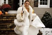 a glam bridal outfit with a strapless mermaid wedding dress, a white faux fur coat and statement earrings for a winter celebration