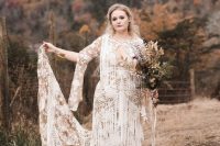 a nude and white boho lace wedding dress with a plunging neckline, long sleeves and lots of fringe covering the dress
