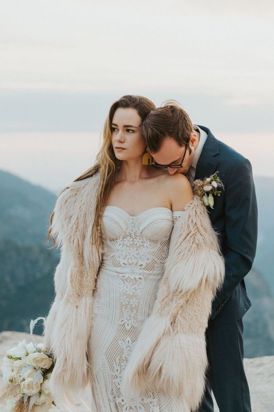 a strapless boho lace wedding dress paired wiht a faux fur coat for a super chic and bold bridal look