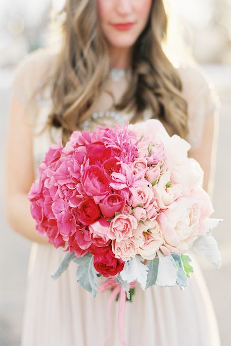 an ombre ball-shaped wedding bouquet from bright pink to red and blush and with pale leaves is a chic and bright idea
