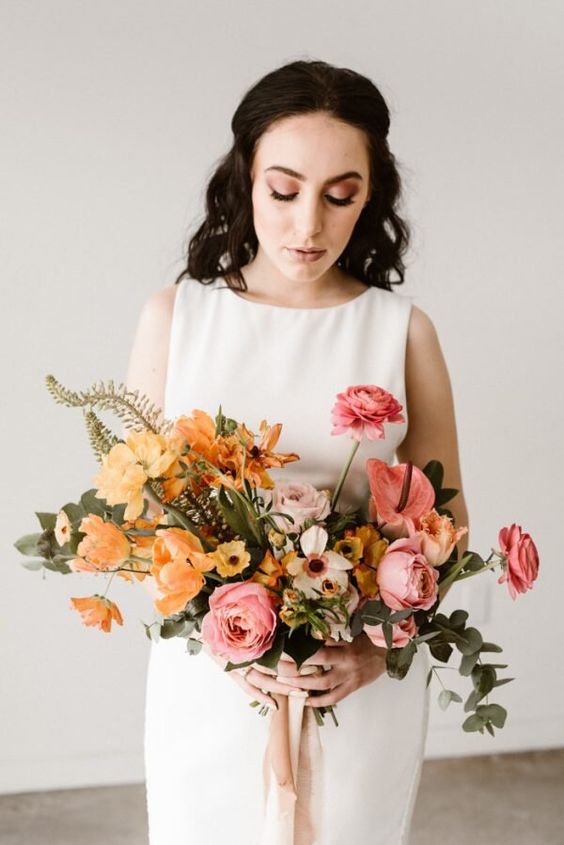 an ombre wedding bouquet from yellow, mustard, light pink and pink blooms and greenery for a modern bride