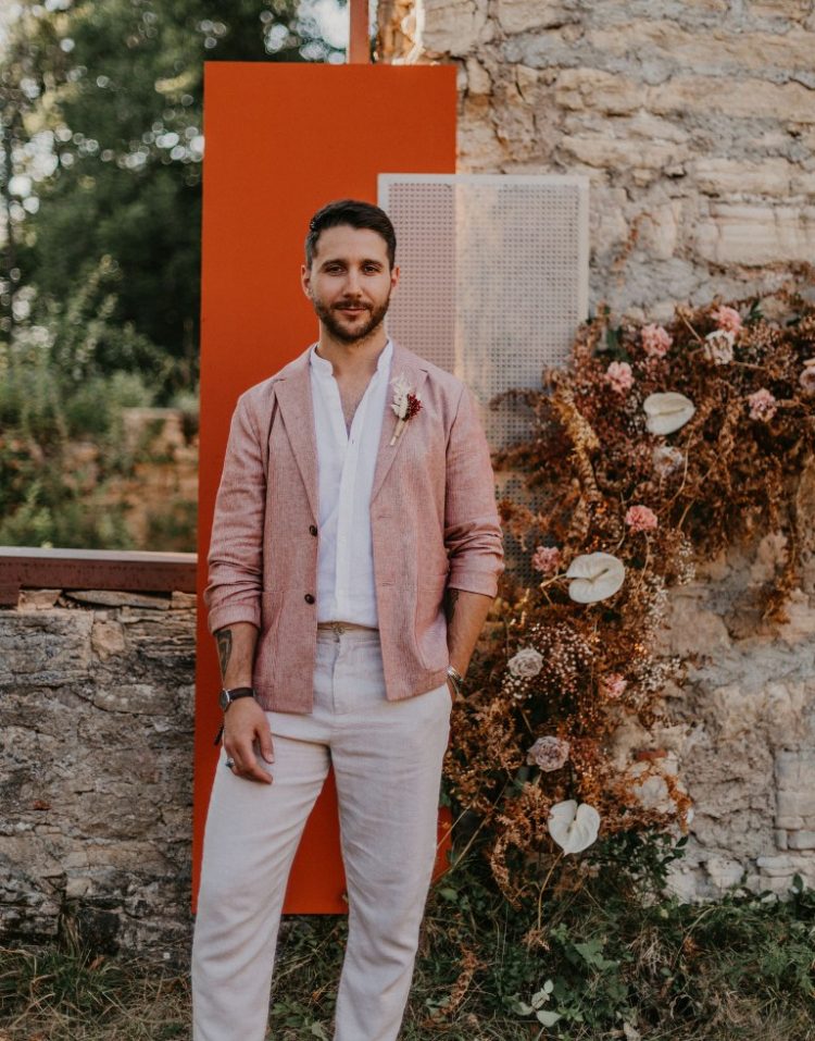 The groom was wearing a terrracotta blazer, a white shirt and pants and brown moccasins