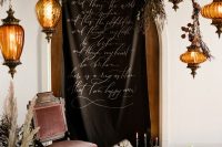 04 The wedding backdrop was done with a custom banner with Poe quotes, moody florals and greenery, candles and hanging lamps