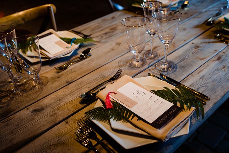 The wedding tablescape was done with an uncovered table, geometric plates and tropical leaves