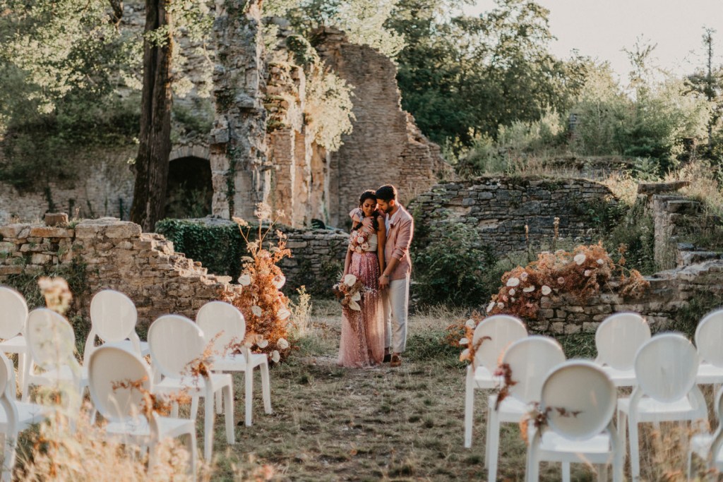 An alternative wedding space   castle ruins decorated with blooms and dried leaves, with white chairs that are very refined