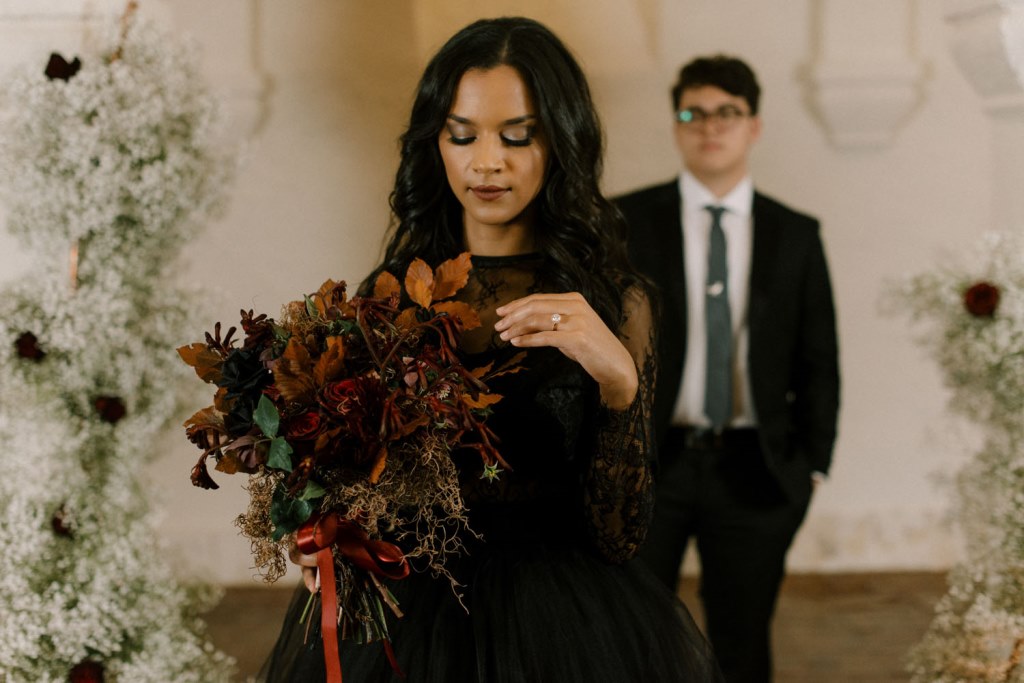 The wedding bouquet was done with dried leaves, dark blooms, moss and herbs plus a red bow