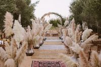 06 The wedding ceremony space was done with pampas grass in silver vases, burlap and boho rugs and a greenery and pampas grass arch