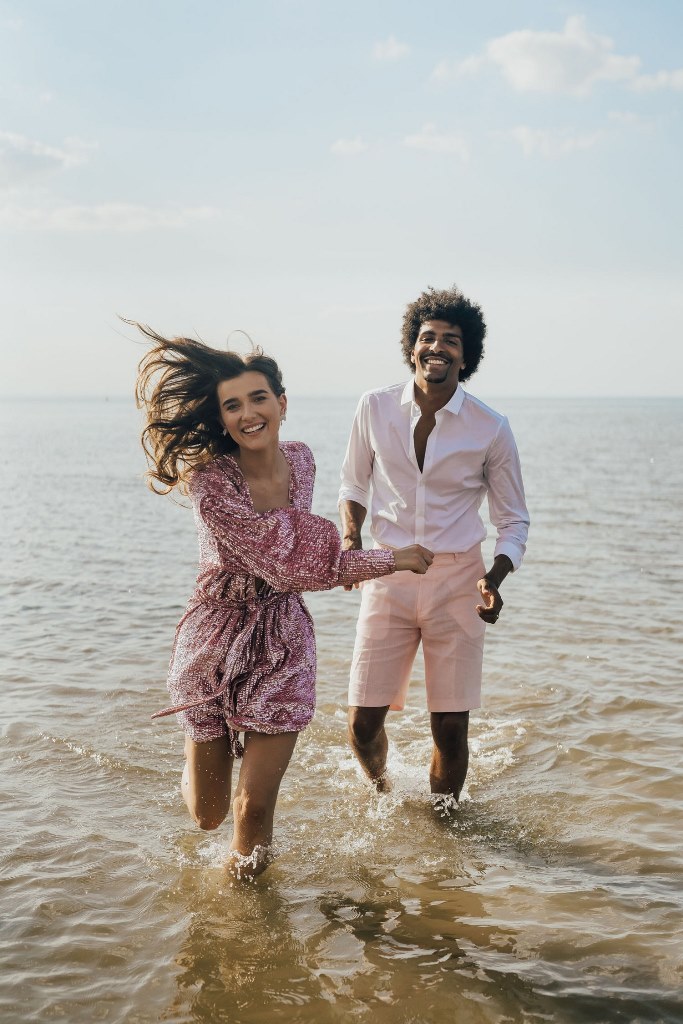 The couple had fun in the sea, the bride was wearing a pink sequin jumpsuit, and the groom rocked pink shorts and a white shirt