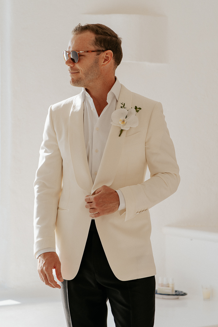 The groom was wearing a simple look of a white shirt, a neutral blazer, black pants and an orchid boutonniere