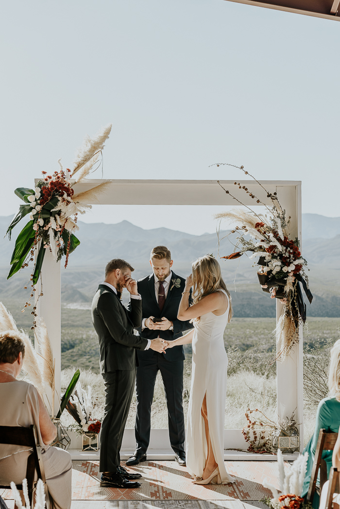 The wedding altar was a white frame with neutral and bold blooms, leaves and pampas grass
