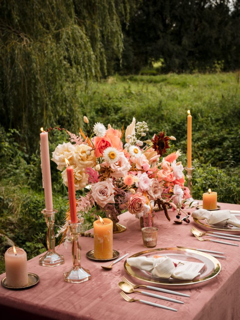 The wedding tables was laid with a mauve tablecloth, some pink blooms, colored candles and gold cutlery and chargers