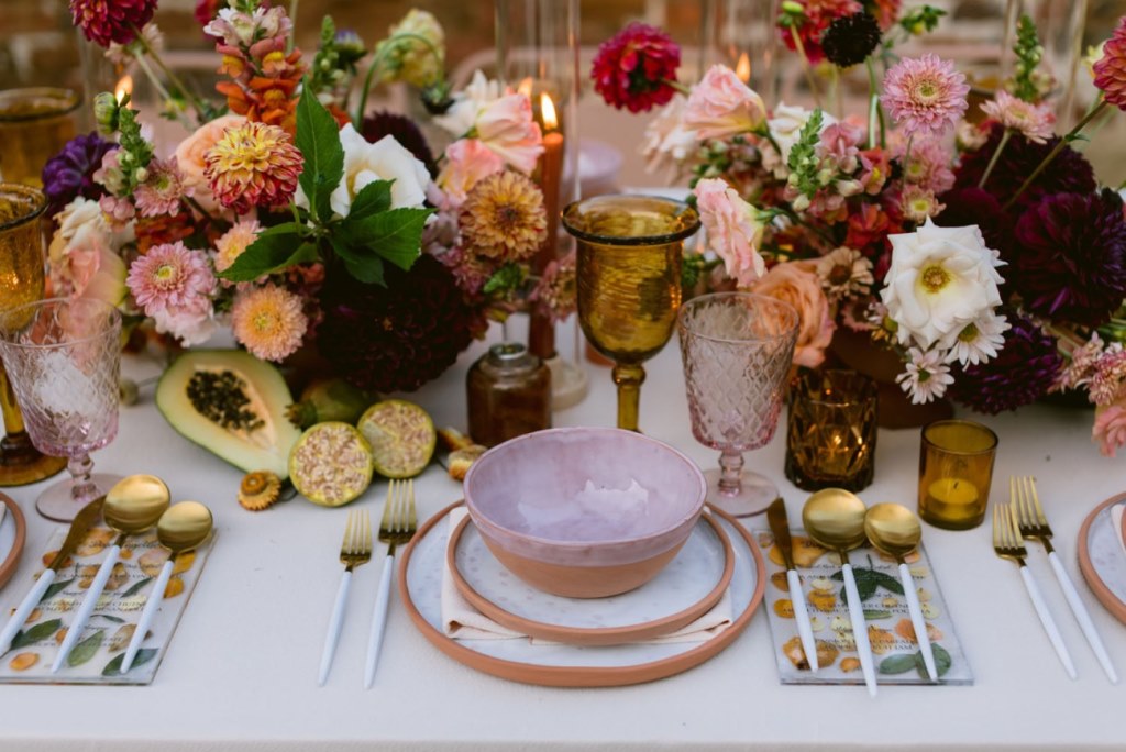 The reception table showed off lush florals, fruits, candles for decor and lovely printed plates and bowls