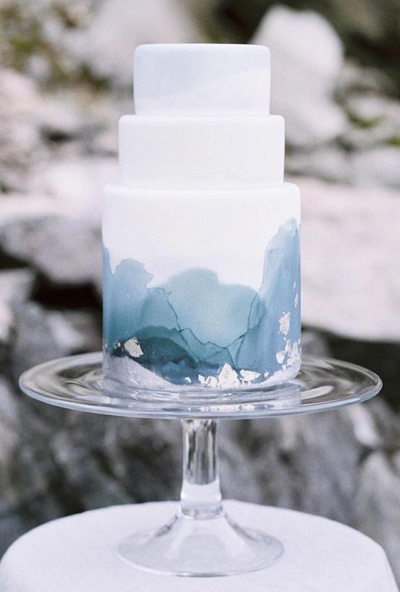 a beautiful coastal wedding cake   a three tier piece with blue watercolor decor and silver leaf is a gorgeous idea
