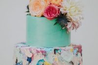 a beautiful colorful wedding cake with a mint green and bold textural brushstroke tier, bold blooms and thistles on top