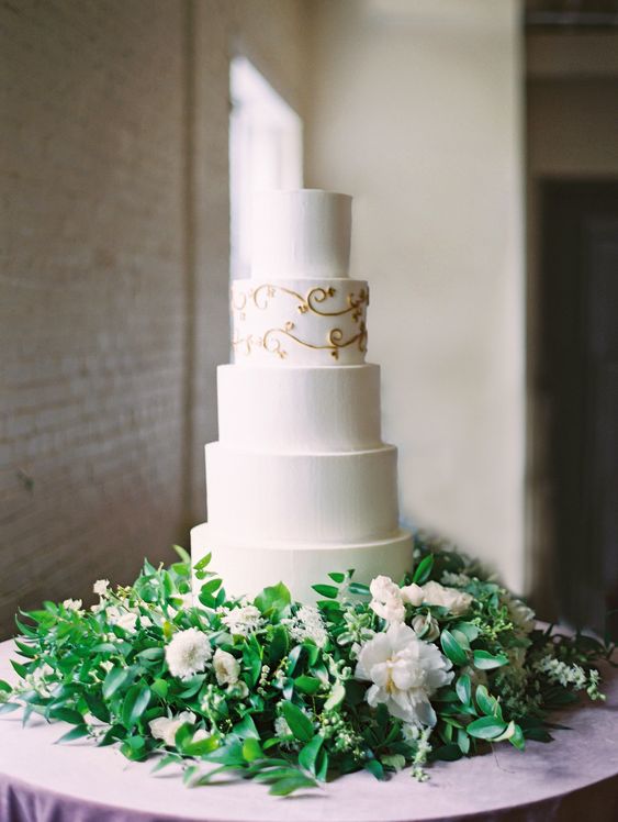 a beautiful five tier wedding cake with white and patterned tiers is a very refined and chic idea, especially served with greenery and white blooms