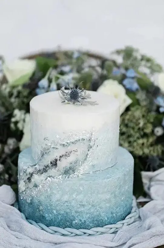 a beautiful ombre ice blue winter wedding cake with crystals and a thistle on top the cake is lovely