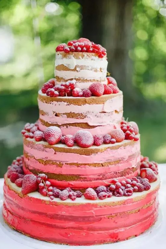 a beautiful red and pink naked wedding cake topped with strawberries and raspberries is a gorgeous idea for a boho summer wedding