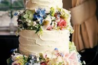 a beautiful white buttercream wedding cake decorated with blush, blue and green blooms, baby’s breath is a lovely idea for a secret garden wedding