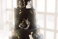 a black celestial wedding cake with gold details, moons, stars and large crystals is a great idea for a celestial wedding