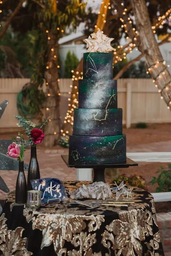 a black, grey and emerald space wedding cake with gold constellations and a whimsical cake topper for a celestial wedding