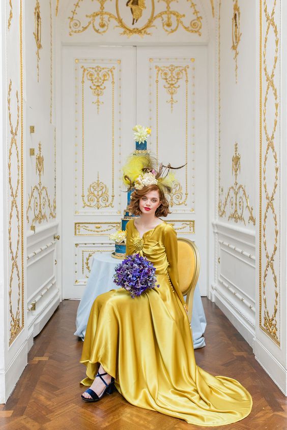 a bold yellow silk A-line wedding dress with a large flower on the bodice and long sleeves for a bold statement
