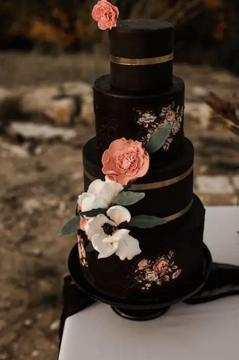 A chic and eye catchy black wedding cake with painted flowers, sugar and fresh blooms, foliage and gold stripes for a fall wedding