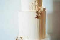 a chic modern fall wedding cake in ivory, with gilded leaves and a pear on top is a lovely idea for a modern or minimal fall celebration