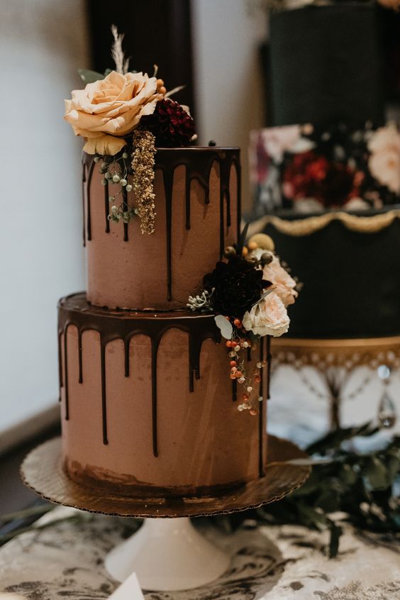 a chocolate wedding cake with chocolate drip, fresh and bold blooms and berries is a decadent piece for a fall wedding