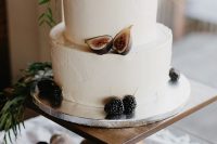 a classic white buttercream wedding cake topped with blackberries and figs plus some berries for the fall
