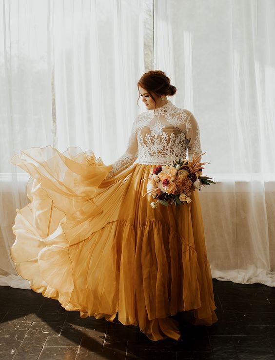 a creative A-line wedding dress with a nude and white lace high neckline bodice and a mustard A-line skirt is a statement