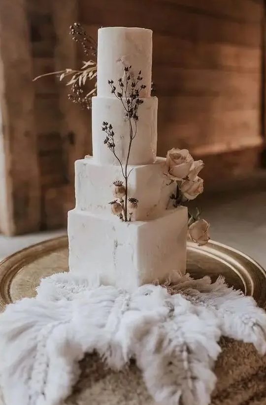 a delicate four tier wedding cake with square and round tiers, sugar patterns, dried blooms and herbs is a stunning idea