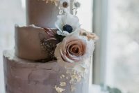a delicate grey textured wedding cake with gold foil, white and blush blooms is a stylish idea for a spring or summer wedding
