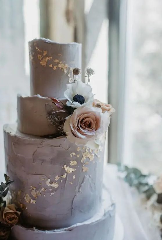 a delicate grey textured wedding cake with gold foil, white and blush blooms is a stylish idea for a spring or summer wedding