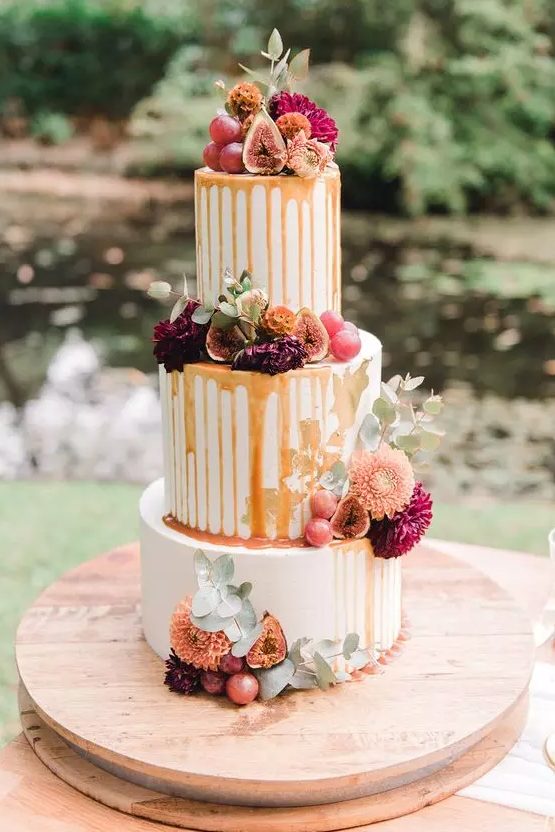 a delicious-looking fall wedding cake with fresh figs and grapes, with burgundy and orange dahlias and caramel drip is a fantastic idea for a fall vineyard wedding