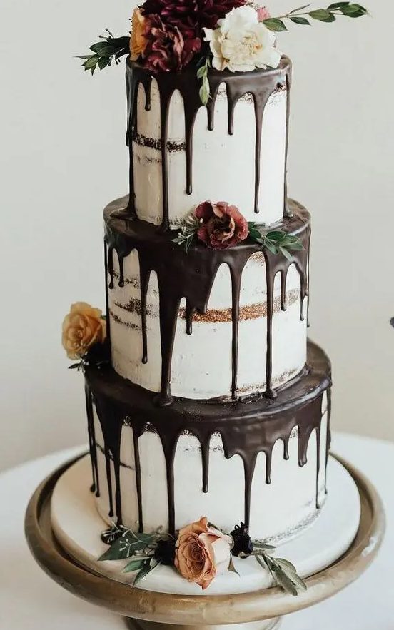 a fantastic three tier naked wedding cake with chocolate drip, blooms, greenery is a gorgeous idea for many weddings